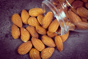 Vintage photo, Heap of fresh healthy almonds spilling out of glass jar on structure of concrete, concept for healthy nutrition