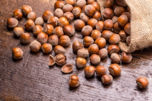 Hazelnuts in burlap bag poured on vintage wooden table